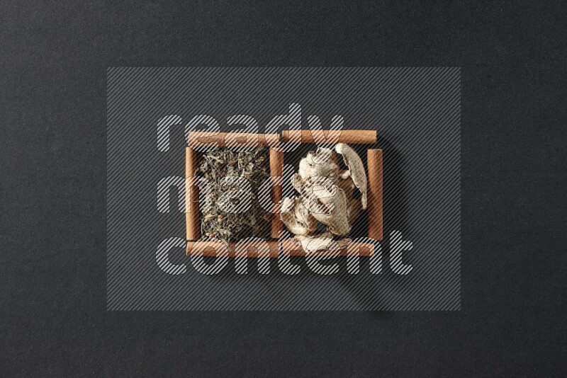 2 squares of cinnamon sticks full of dried ginger and dried basil on black flooring