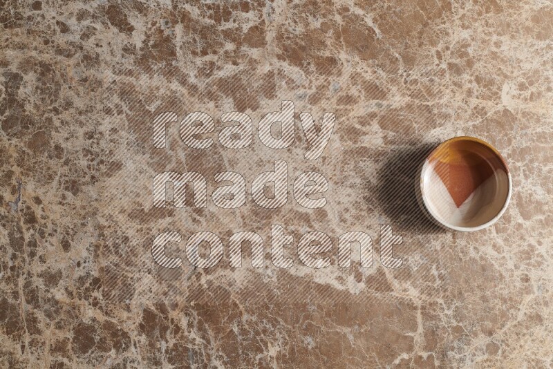A multicolored pottery bowl on beige marble background