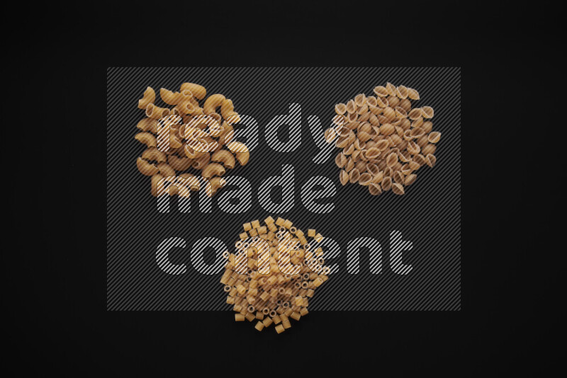 Different pasta types in bunches on black background