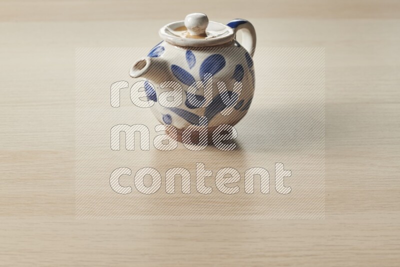 A pottery teapot on light wooden background