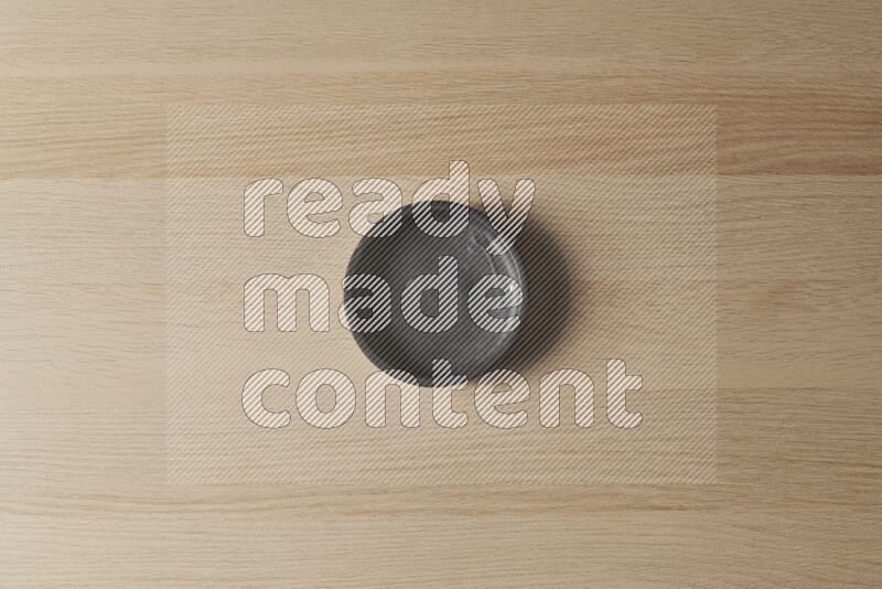 A black pottery bowl on light wooden background