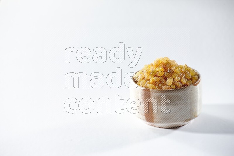 A beige ceramic bowl full of raisins on a white background in different angles
