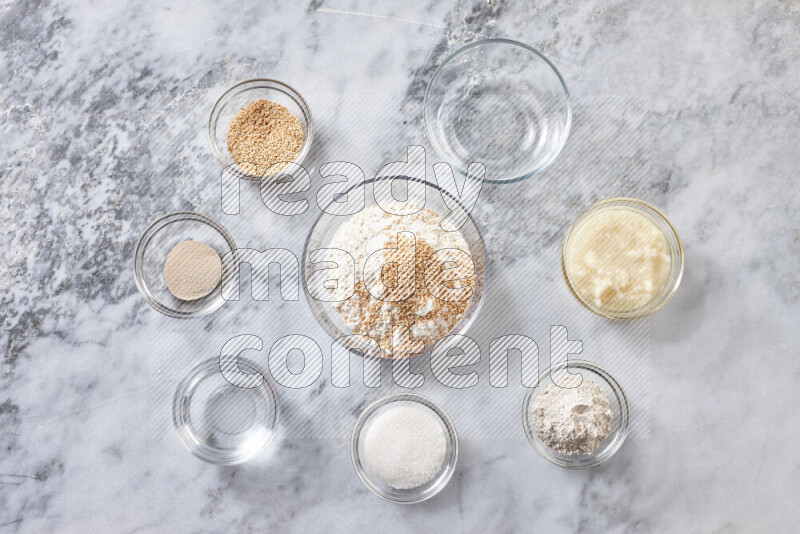 Kahk step by step with its ingredients ghee, sugar, flour, sesame, yeast, water and kahk flavor on grey marble background