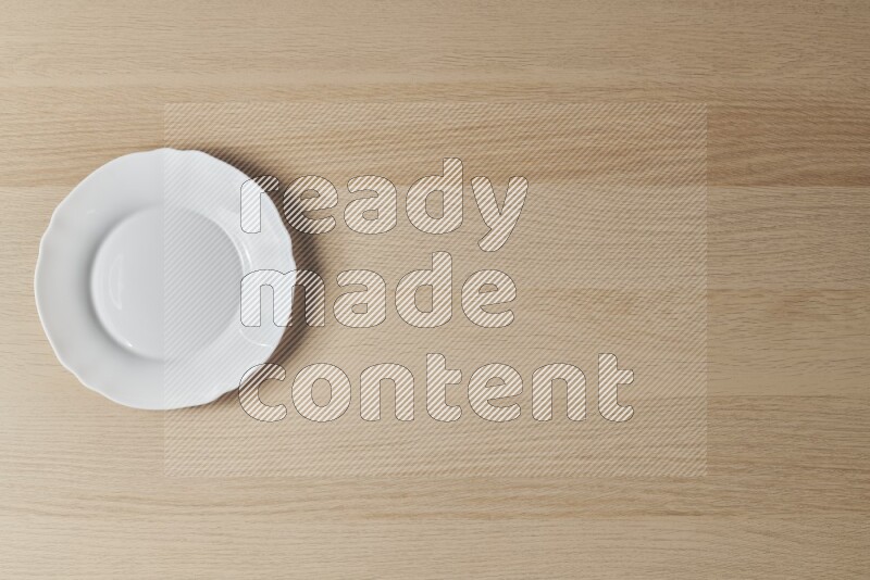 A white ceramic circular plate on light wooden background
