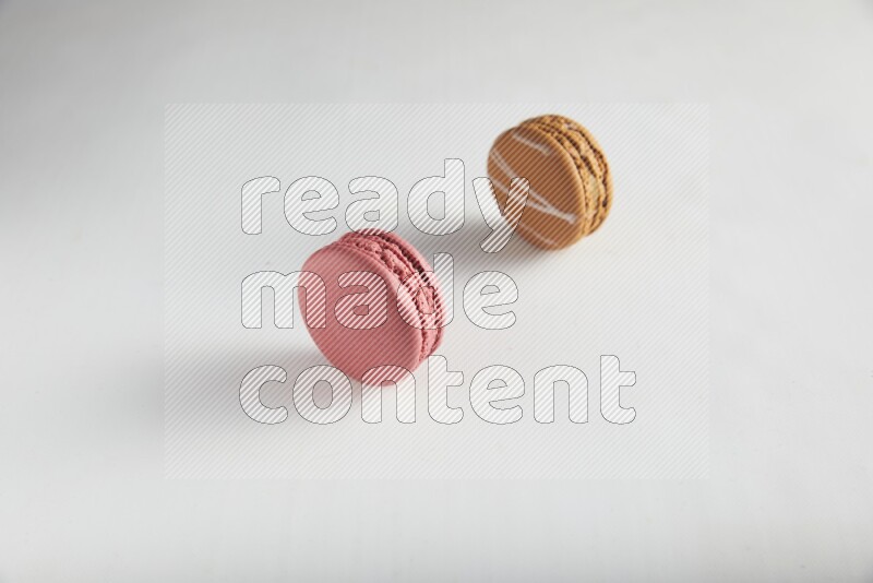 45º Shot of of two assorted Brown Irish Cream, and Pink Raspberry macarons on white background