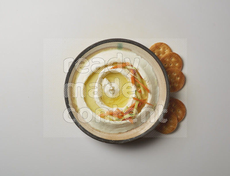 Lebnah garnished with sliced carrots &cucumber in a pottery plate on a white background