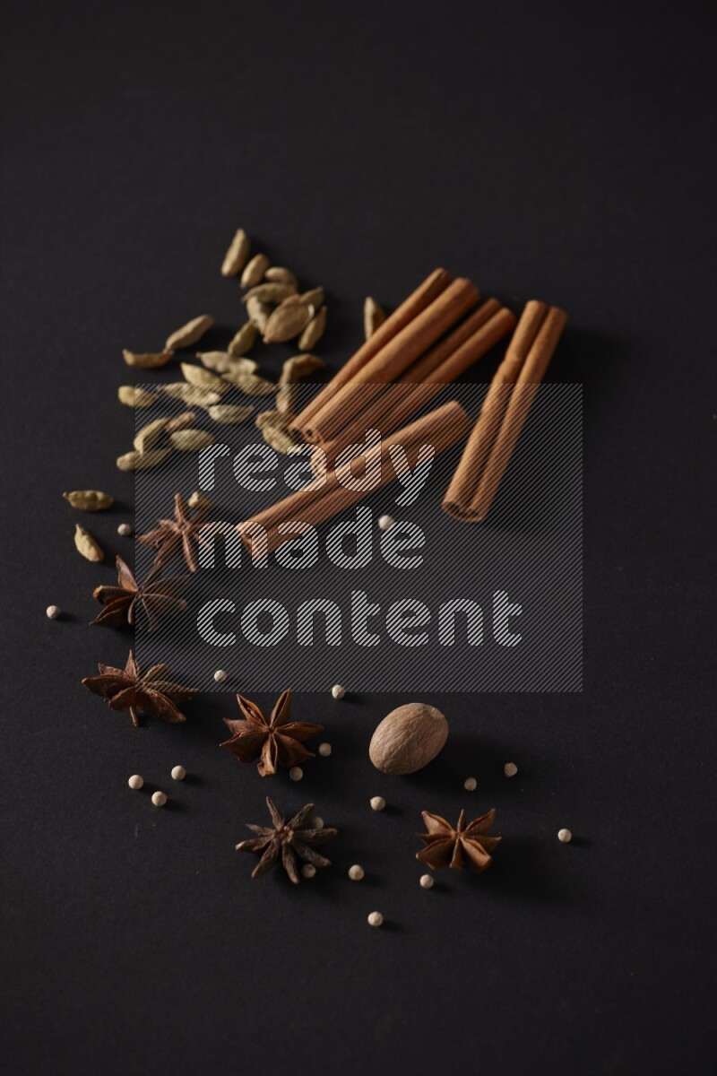 Cinnamon sticks, cardamom, star anise, nutmeg and white peppers on a black background