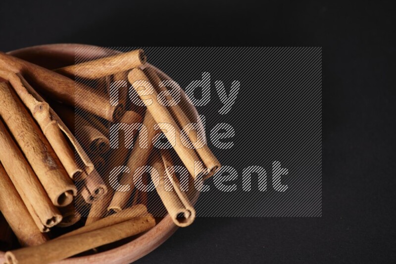 Cinnamon Sticks in a wooden bowl on black background