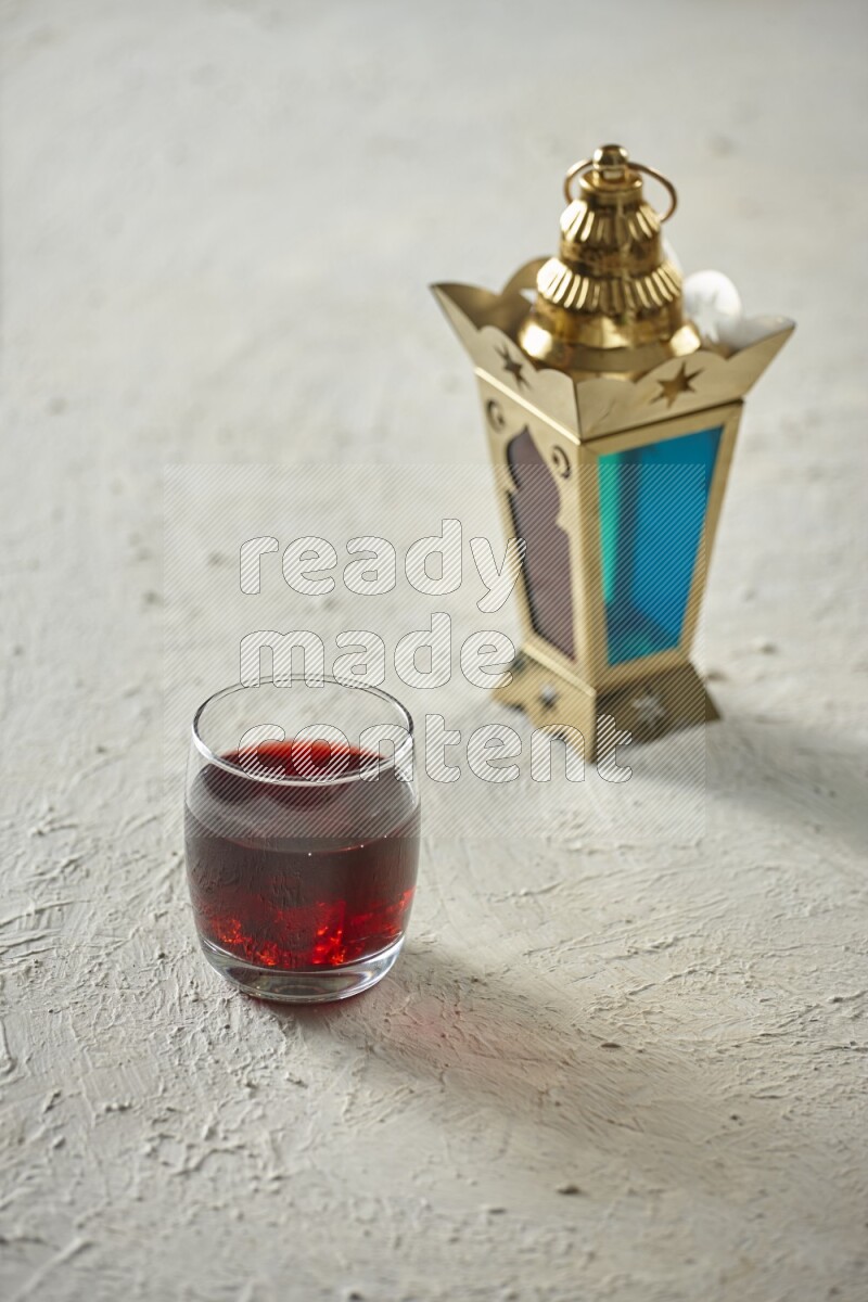 A golden lantern with different drinks, dates, nuts, prayer beads and quran on textured white background