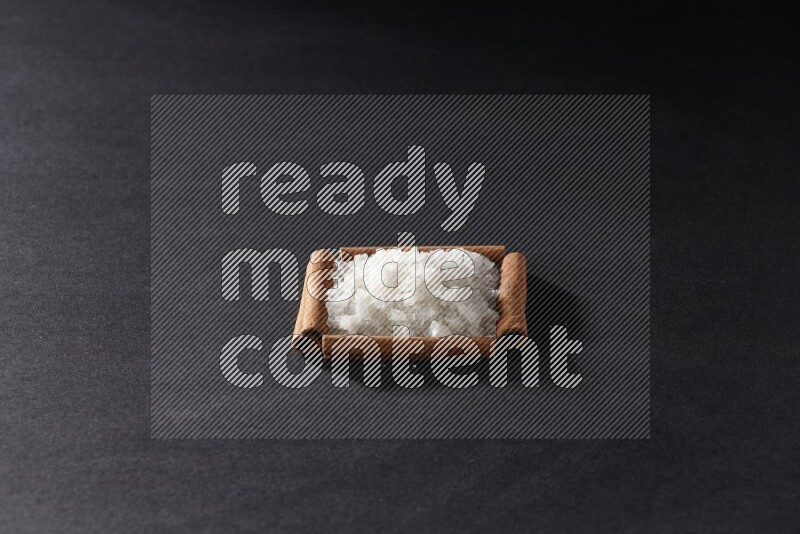 أربعة من أعواد القرفة مكونة شكل مربع بداخلها ملح أبيض علي خلفية سوداء