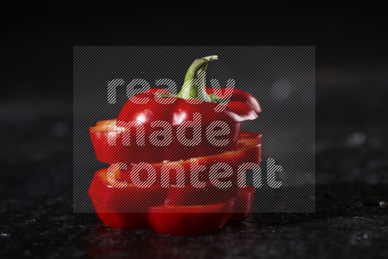 Red bell pepper slices on black background
