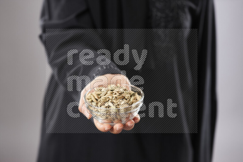 Woman in abaya holding different kinds of spices in different positions
