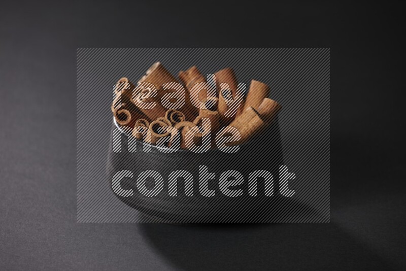 Cinnamon sticks in a black bowl on a black background in different angles