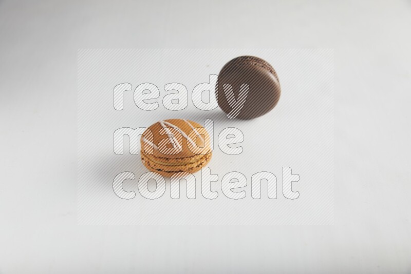 45º Shot of of two assorted Brown Irish Cream, and Brown Dark Chocolate macarons on white background