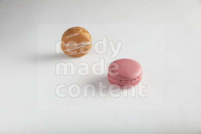 45º Shot of of two assorted Brown Irish Cream, and Pink Raspberry macarons on white background