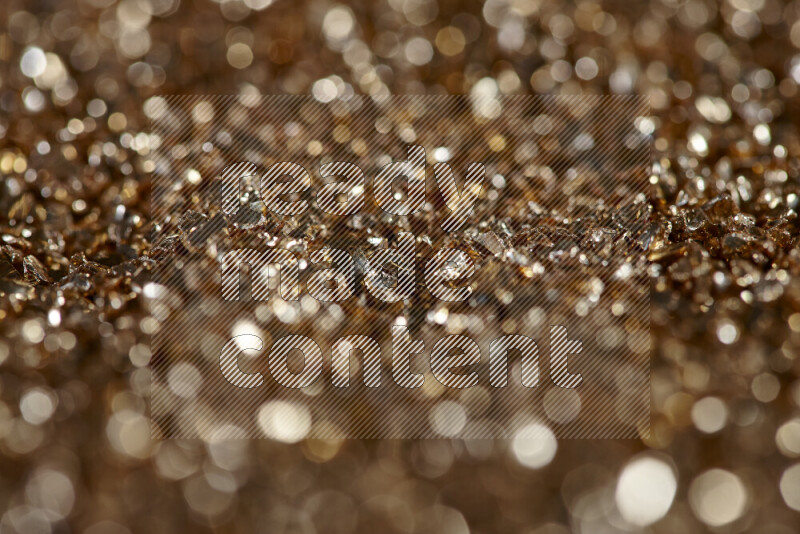 Gold shimmering fragments of glass scattered on a black background