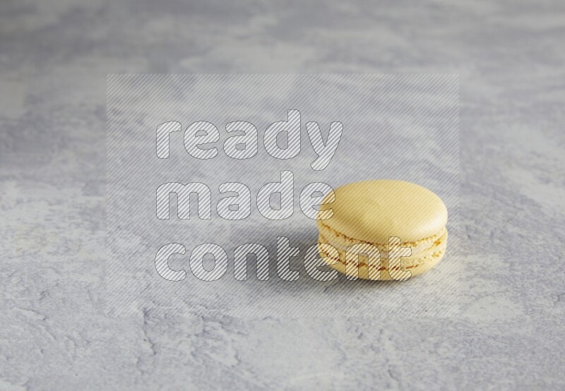 45º Shot of Yellow Vanilla macaron on white  marble background