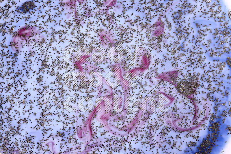 لقطة مقربة لبريق ذهبي متلألئ منتشر على خلفية من اللون الأزرق والأحمر في حركات دائرية