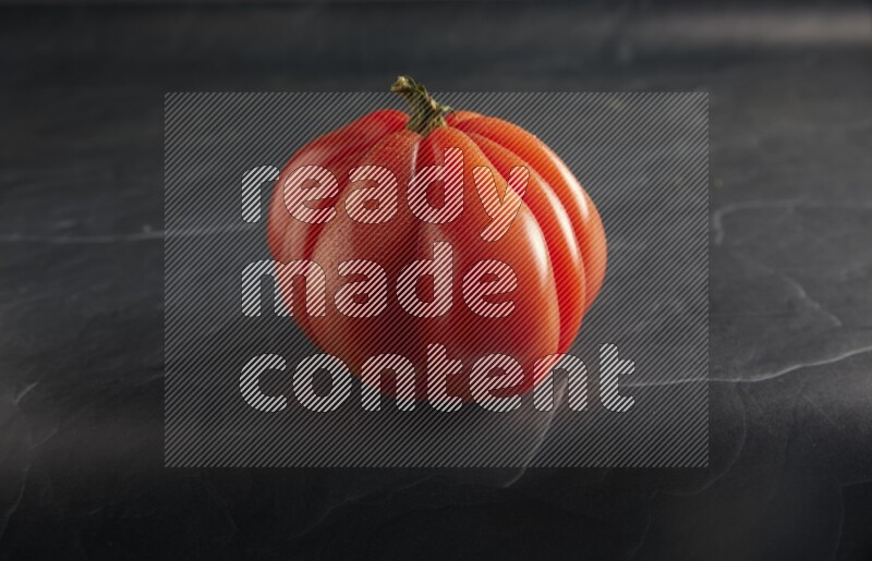 45 degree single heirloom tomato on a textured black slate background
