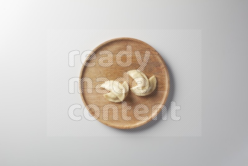 Four Sambosas on a wooden round plate on a white background
