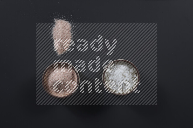 2 pottery bowls one is filled with himalayan salt and the other with white salt on black background