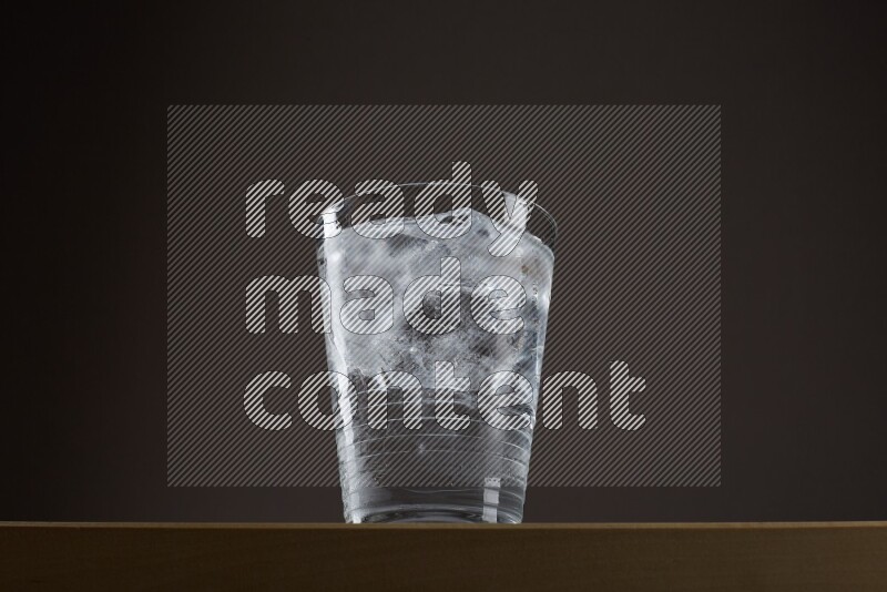 Low angle shot of a glass of water and ice on grey background