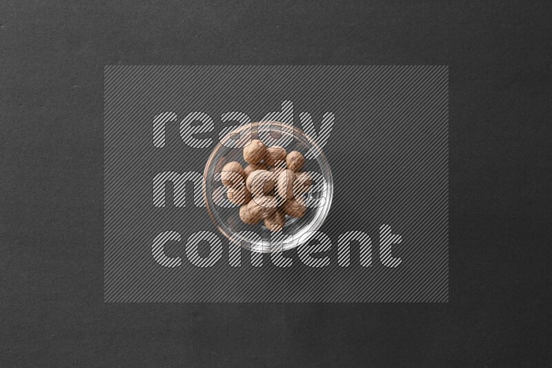 A glass bowl full of nutmeg on black flooring