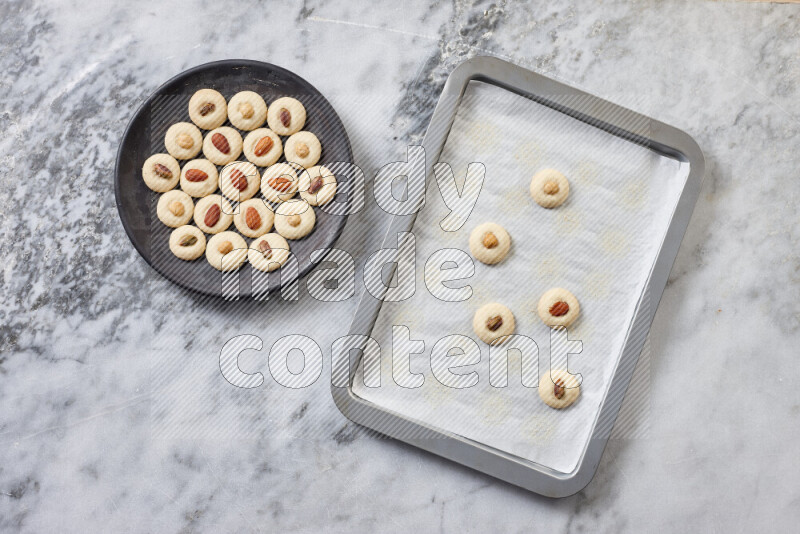 Ghoriba step by step with its ingredient, flour, powdered sugar, ghee and nuts on grey marble background