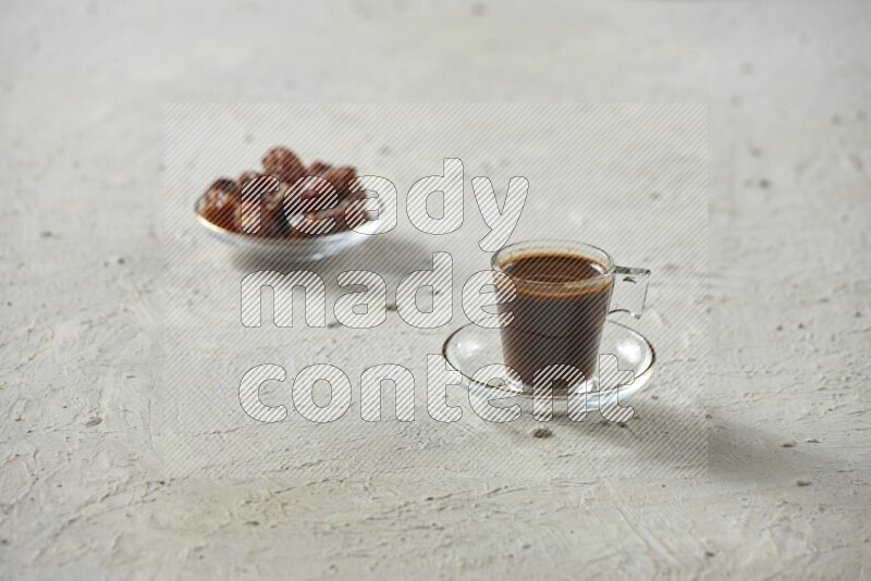A coffee glass cup with dates and tea on textured white background