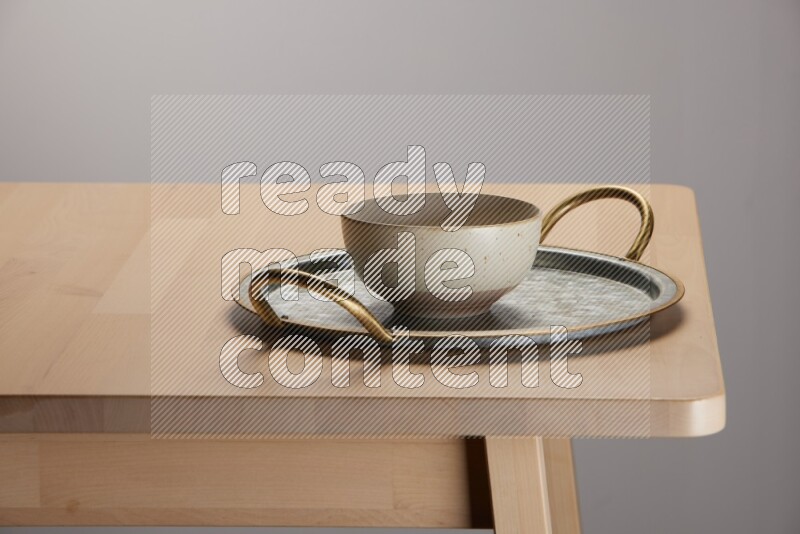 multicolored bowl placed on a rounded stainless steel tray with golden handels on the edge of wooden table