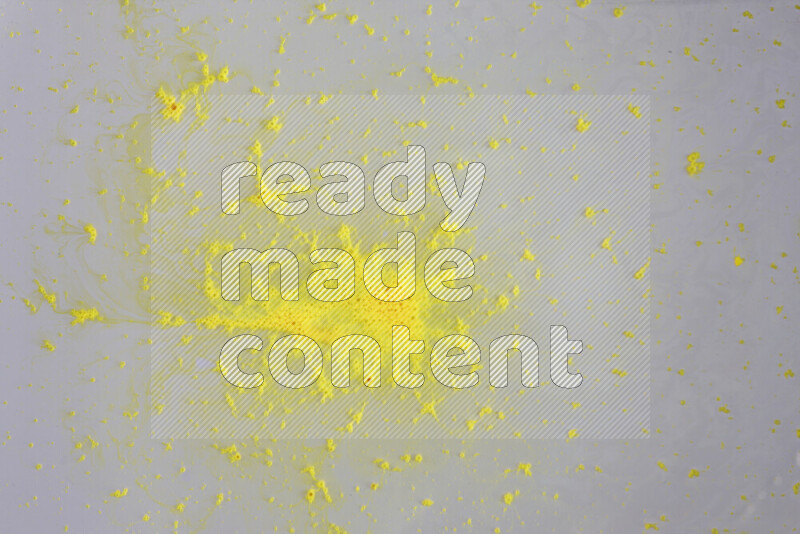 The image captures a dramatic splatter of yellow paint over a white backdrop