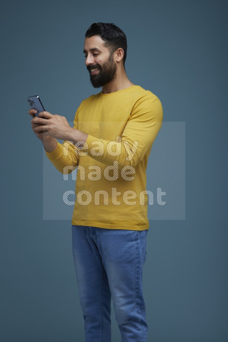 Man typing on his phone in a blue background wearing a yellow shirt
