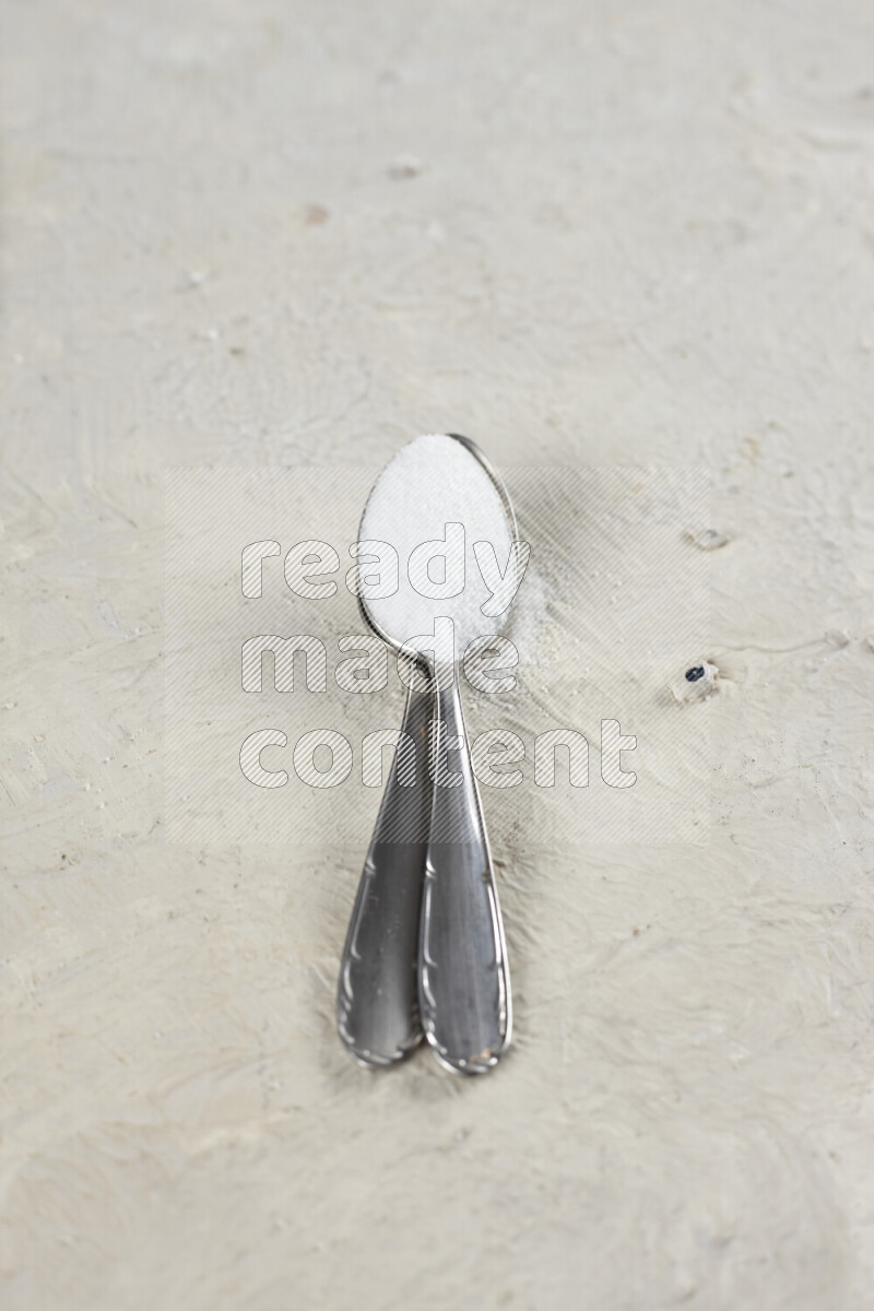 2 metal spoons filled with fine table salt and fine pink himalayan salt on white background