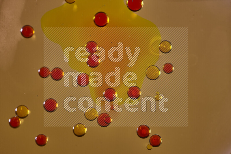 Close-ups of abstract yellow and red watercolor drops on oil Surface on yellow background