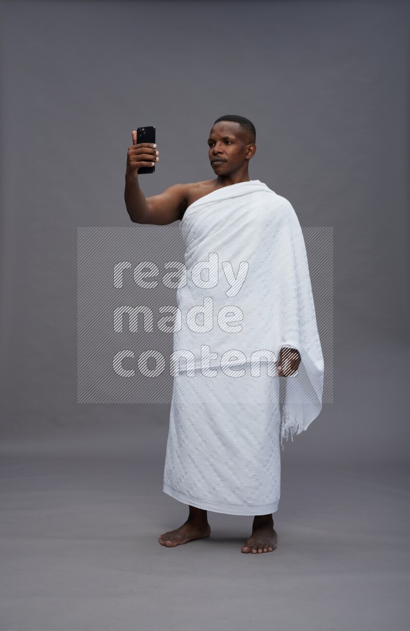 A man wearing Ehram Standing taking selfie on gray background