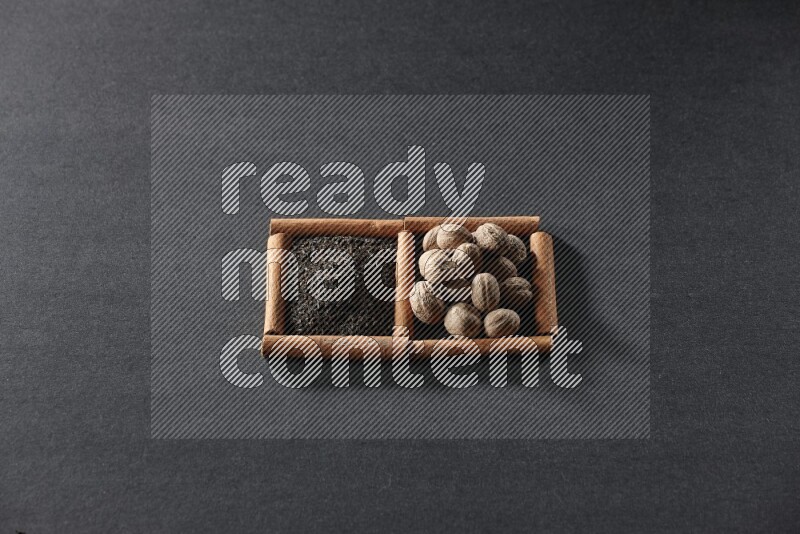 مربعان من أعواد القرفة ممتلئان بالشاي وجوزة الطيب علي خلفية سوداء