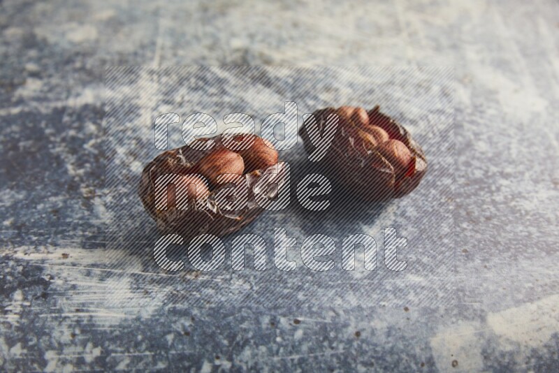 two hazelnuts stuffed madjoul dates on a rustic blue background