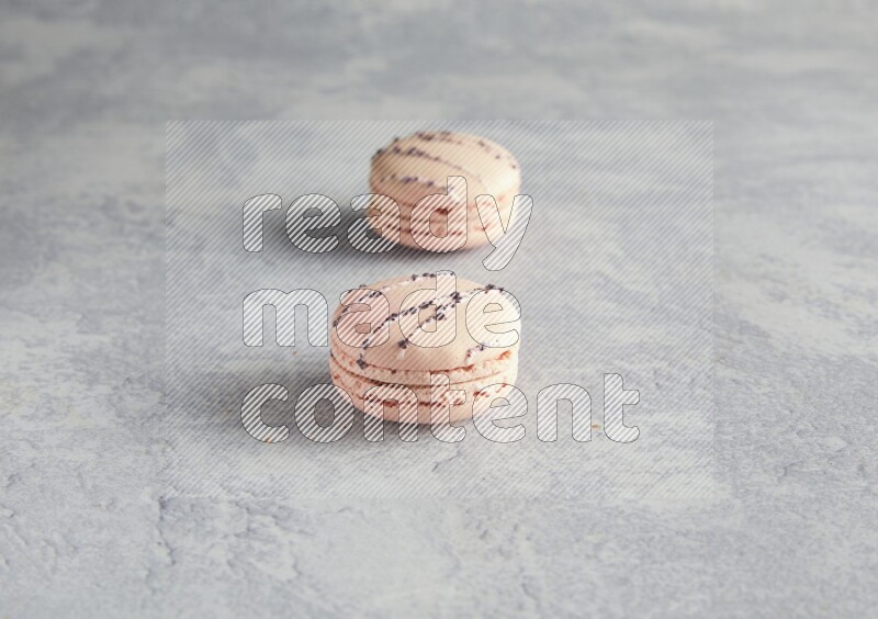 45º Shot of two pink orange blossom macarons  on white  marble background
