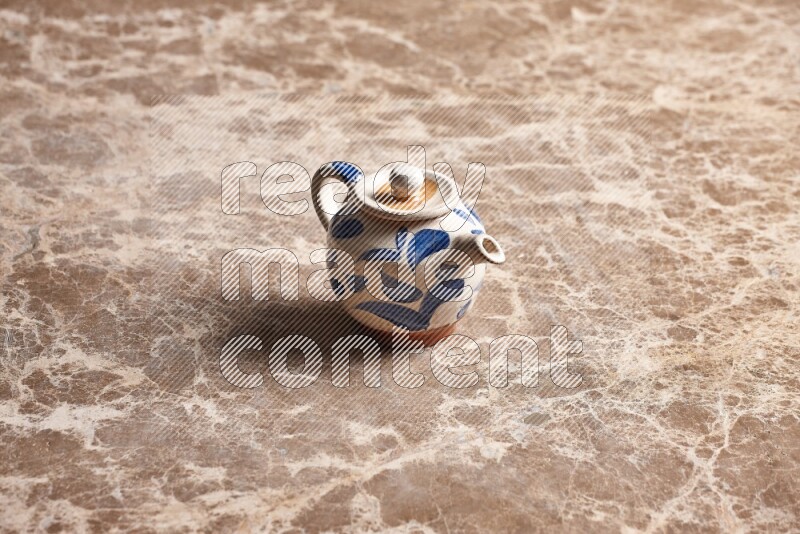 A pottery teapot on beige marble background