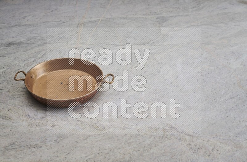 A small copper pan on grey marble background