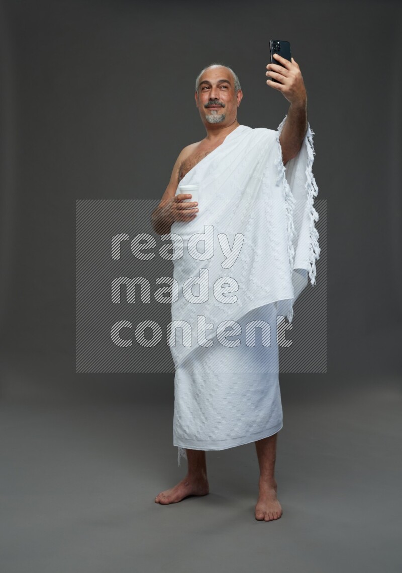 A man wearing Ehram Standing taking selfie on gray background
