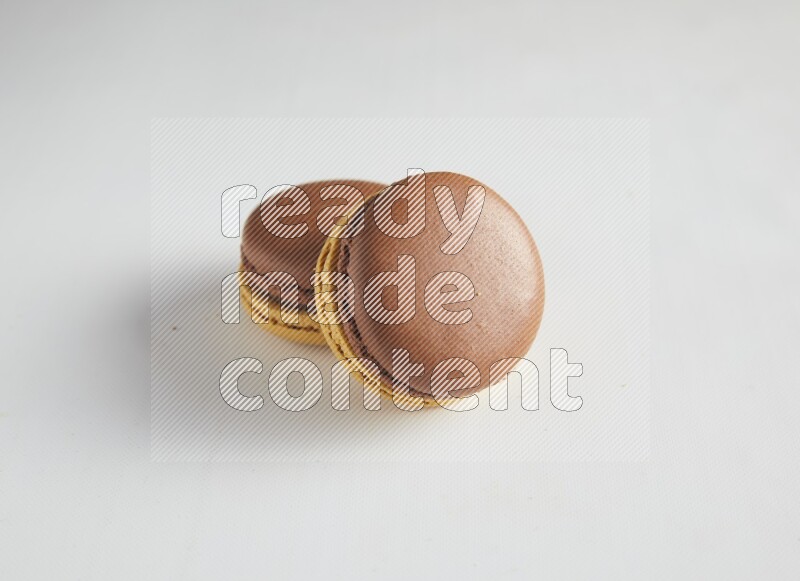 45º Shot of two Yellow and Brown Chai Latte macarons on white background