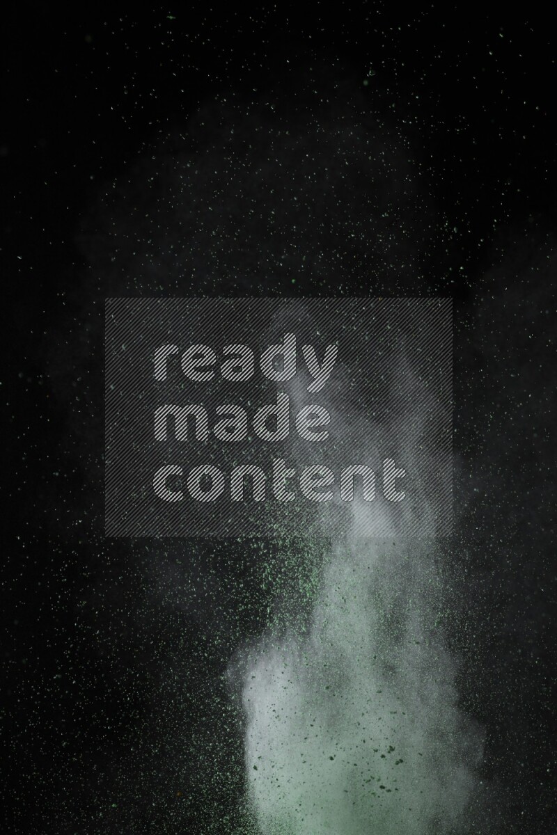 A side view of green powder explosion on black background