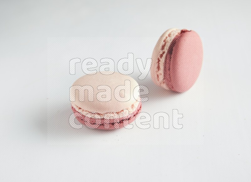 45º Shot of two Pink Litchi Raspberry macarons on white background