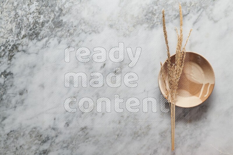Wheat stalks on multicolored pottery plate on grey marble background