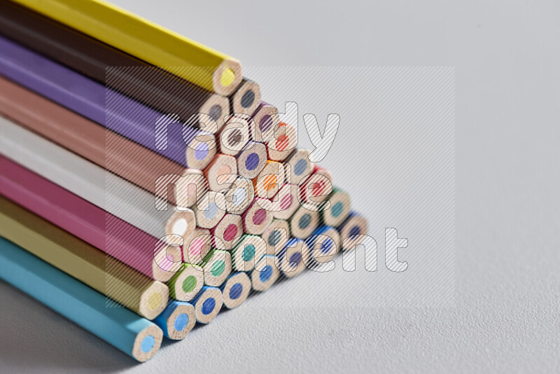 A close-up of the tips of colored pencils arranged in a bundle on white background