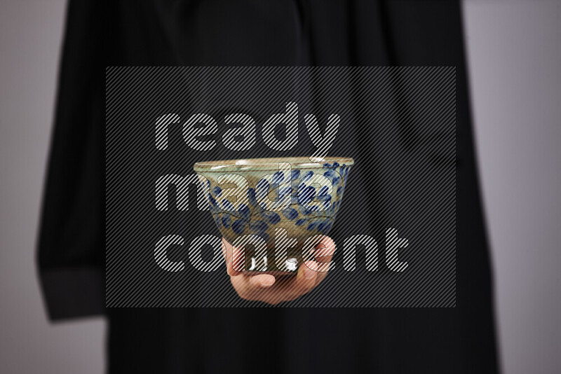 A woman in black abaya holding different pottery essentials in different positions