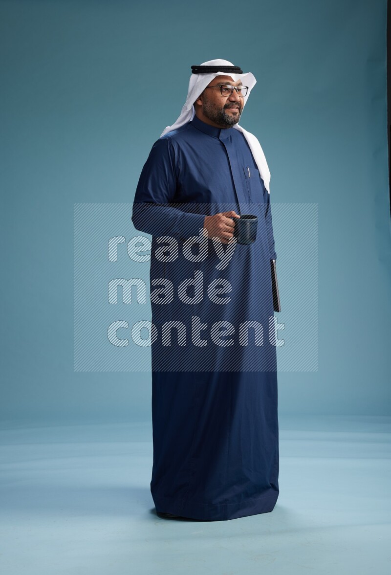 Saudi Man with shimag Standing drinking coffee on blue background