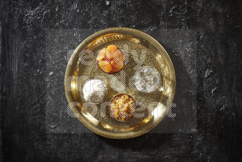 فواكه مجففة في أطباق معدنية مع الماء على صينية علي خلفية سوداء