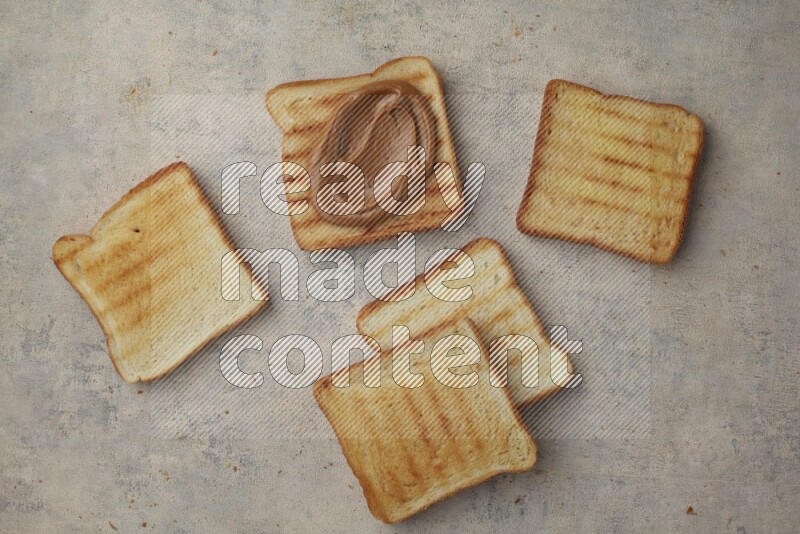 Creamy peanut butter on a toasted white toast and toasted white toast slices on a light blue textured background